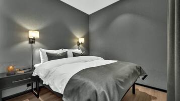 Un dormitorio moderno con una cama, dos lámparas de noche, una mesita de noche y una mesa de noche con lámpara.