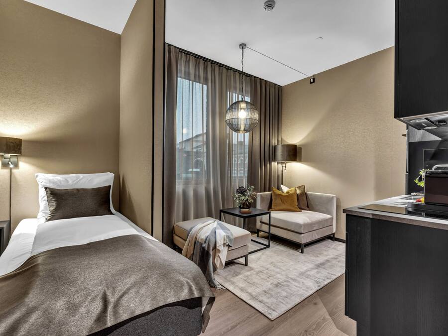 A modern hotel room with a bed, a desk, a chair, and a large window with curtains.
