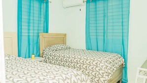 A bedroom with two beds, a wooden headboard, a small bedside table, and a white crib. - Cozy house with 3 bedrooms, a 10-minute walk to the Samana boardwalk. (Samaná)