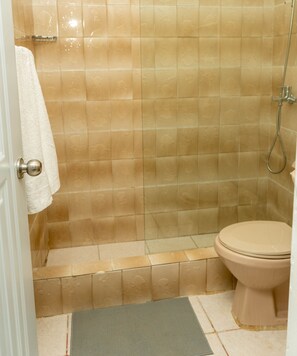 A bathroom with beige tiles, a white toilet, and a shower area.