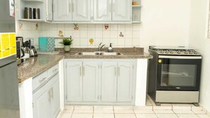 A kitchen with white cabinets, a granite countertop, a stove, and a sink. - Cozy house with 3 bedrooms, a 10-minute walk to the Samana boardwalk. (Samaná)