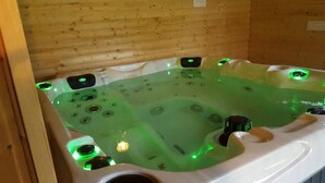 A hot tub with multiple jets, green lighting, and a wooden interior. - Ottenskamp4 en Het Achterhuis (Siebengewald)