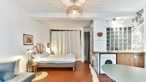 Une pièce de taille modeste comprenant un lit, un canapé, une table à manger et un lave-linge.