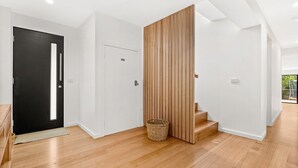 Un interno moderno con una porta nera, pareti bianche e una scala in legno.