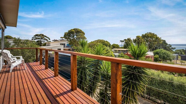 A wooden deck with a railing, overlooking a residential area with houses and trees. - Sea to Sunset View in Ventnor (Ventnor)