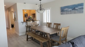 Un coin repas avec une table et des chaises en bois, un luminaire suspendu et un tableau au mur.