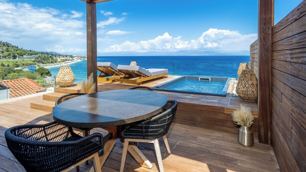 Eine Holzterrasse mit Pool, Liegestühlen und einem Tisch.