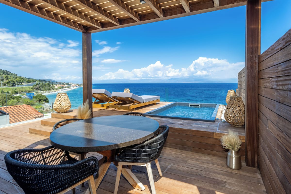 Eine Holzterrasse mit Pool, Liegestühlen und einem Tisch.