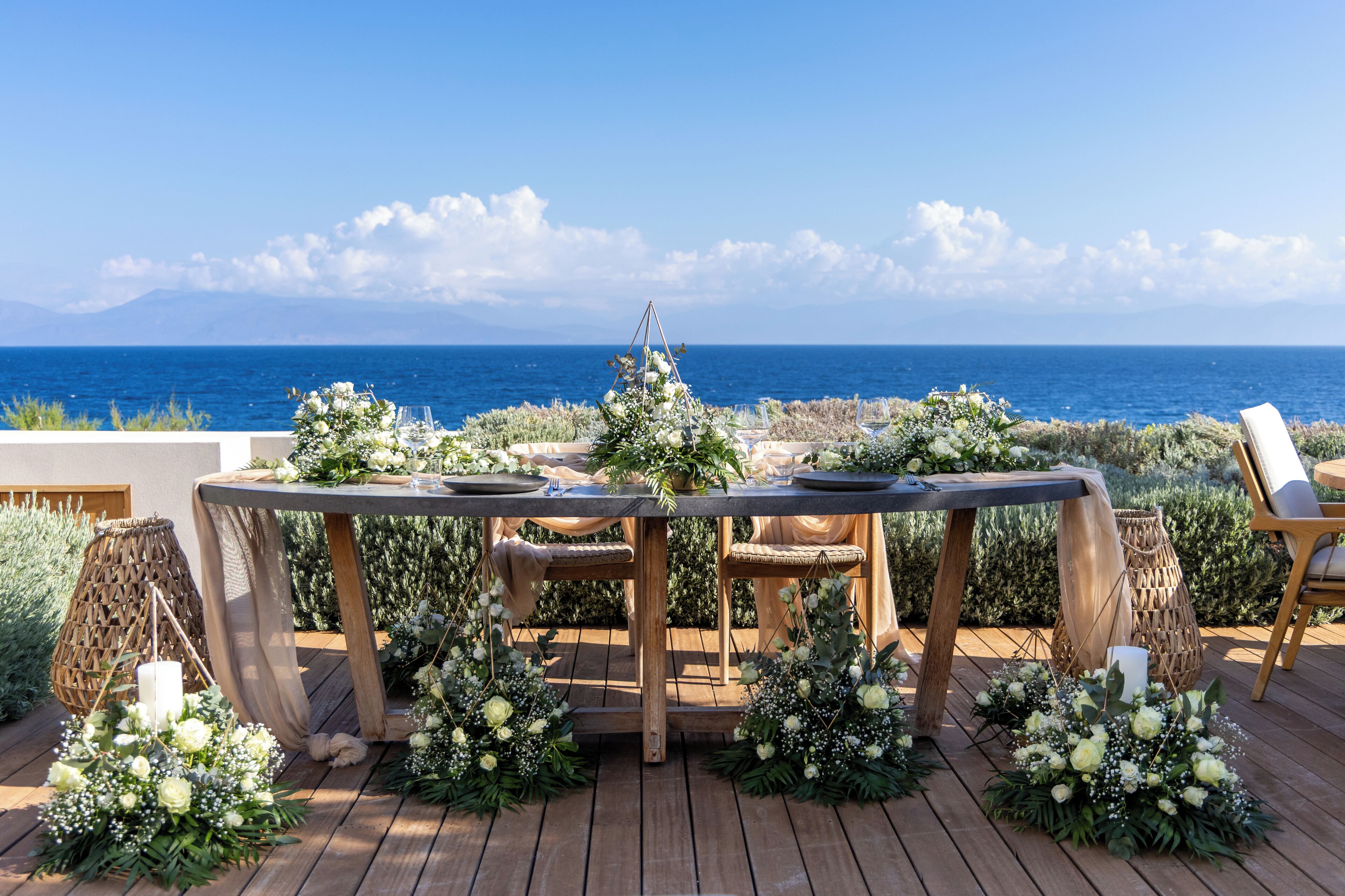 Une terrasse en bois avec une table dressée pour le repas, offrant une vue sur la mer.
