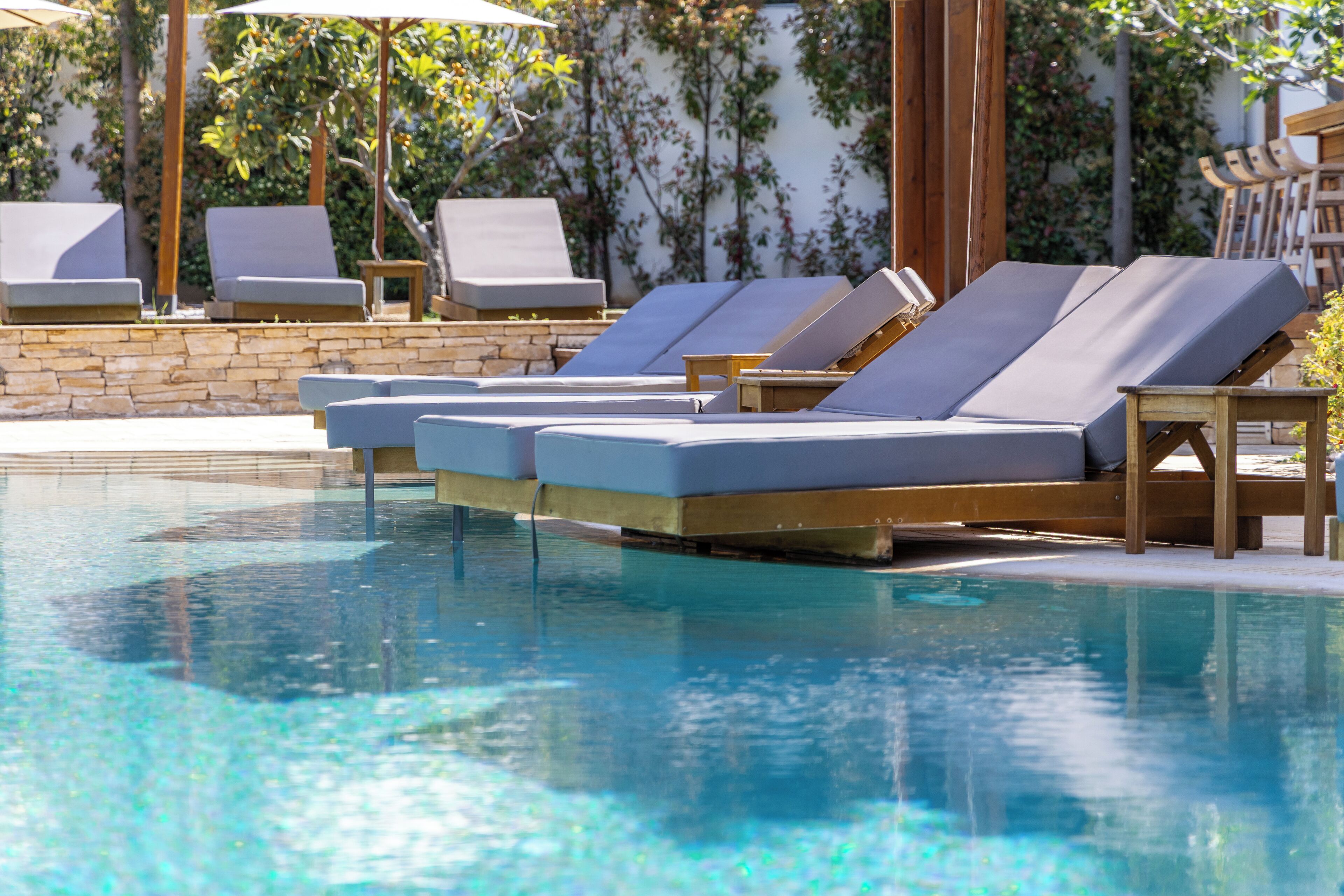 Uma área de piscina com espreguiçadeiras e uma parede de pedra.