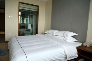 A hotel room with a large bed, a bedside telephone, and a bathroom visible through an open door. - Jinpeng Baisid Huamu Holiday Hotel (Lai'an)