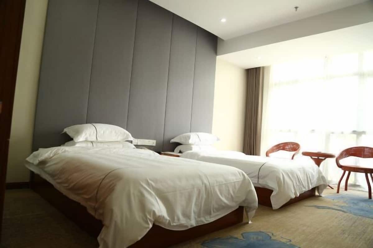 Une chambre d’hôtel avec deux lits, une petite table et une chaise.