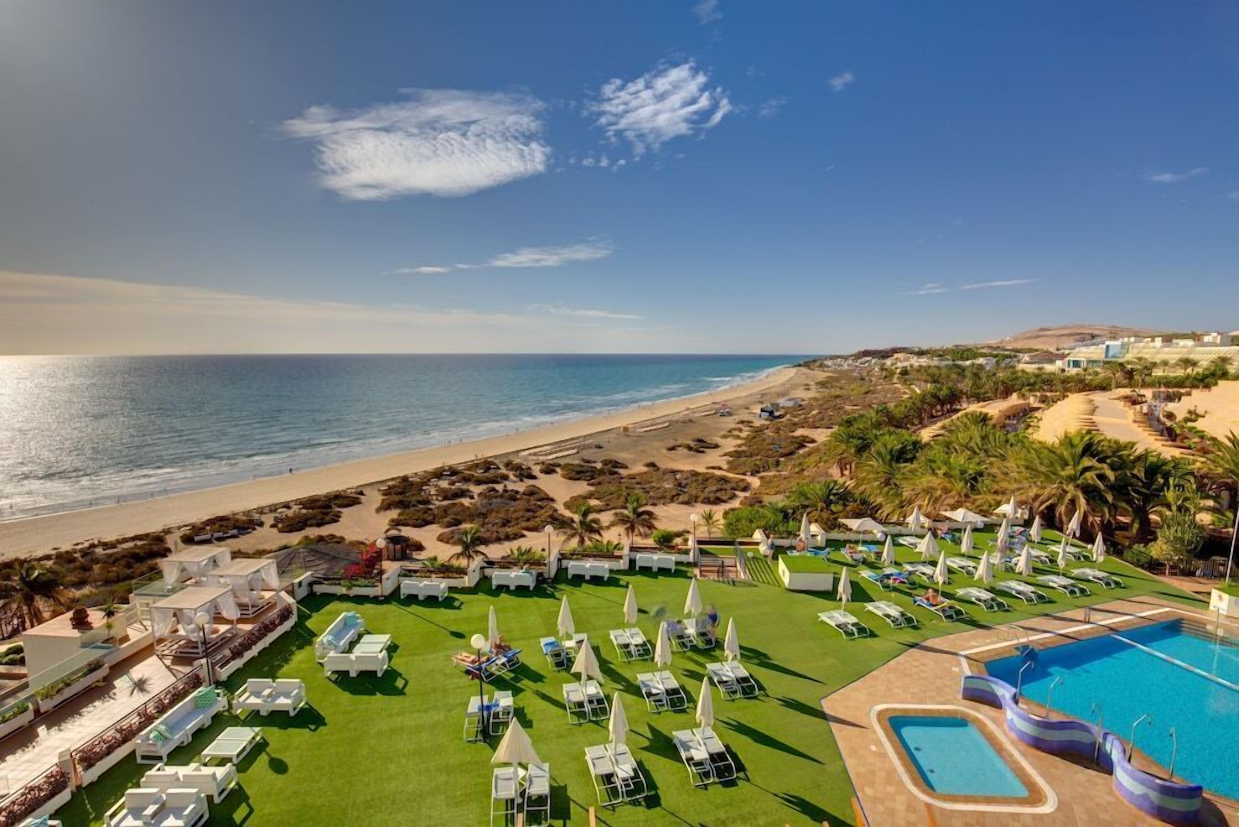 Un complexe hôtelier doté d’une piscine, de chaises longues et offrant une vue sur la plage.