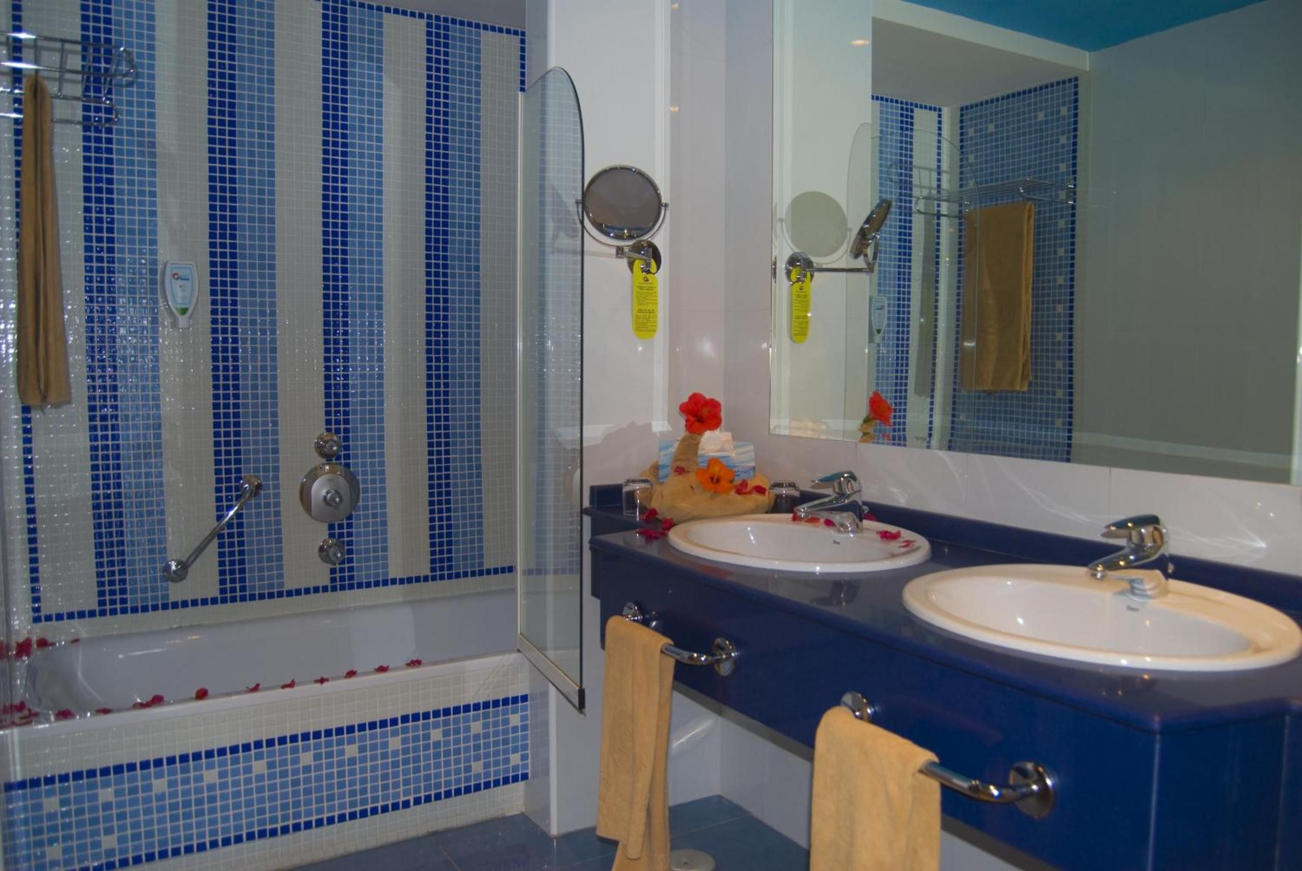 A bathroom with a glass shower enclosure, two sinks, and a large mirror.