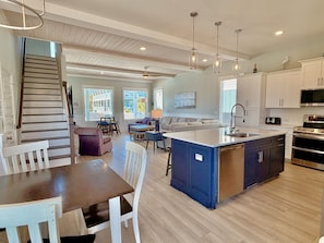A spacious kitchen with a central island, white cabinetry, and a dining area with a table and chairs.