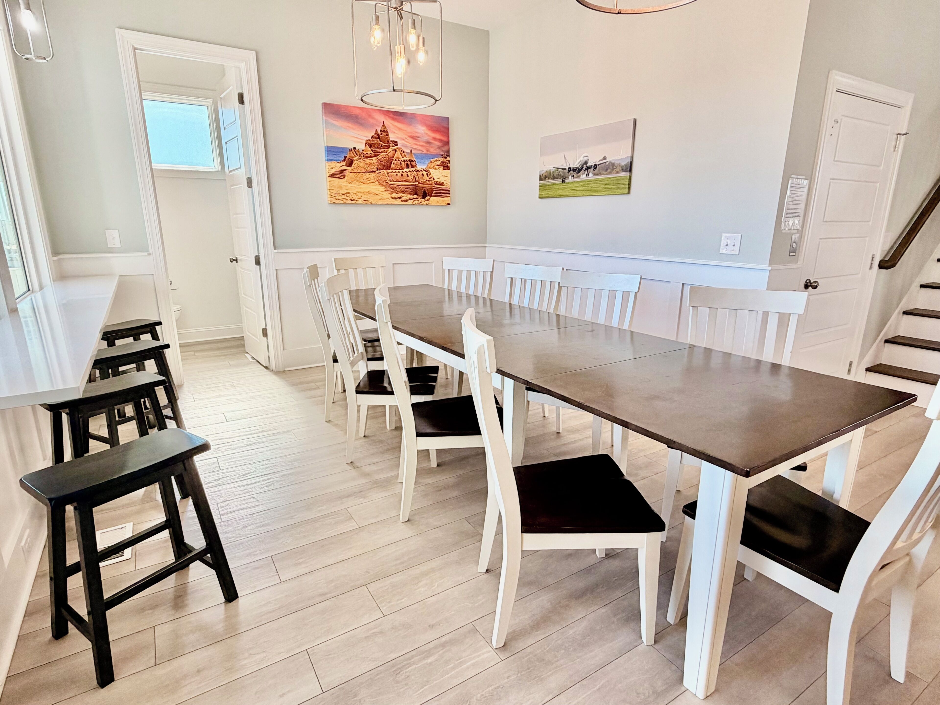A dining area with a long table, white chairs, and a wooden bench.