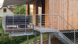 Een modern houten gebouw met een balkon en een overdekt terras.