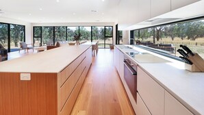 A modern kitchen with a large island, ample natural light, and a view of the outdoors. - Lawson Lodge - Modern home minutes from Lake Eildon (Mansfield)