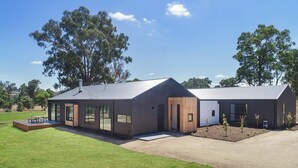 A modern building with large windows, a flat roof, and a small deck area. - Lawson Lodge - Modern home minutes from Lake Eildon (Mansfield)