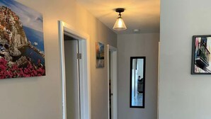 A hallway with wooden flooring, white walls, and a ceiling light fixture. - Lake Simcoe Beach Oasis with Backyard and Firepit (Willow Beach)