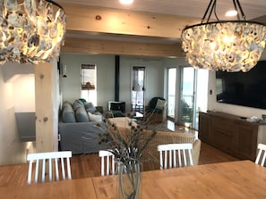Uma sala de estar espaçosa com uma grande mesa de jantar de madeira, um sofá e uma televisão na parede.