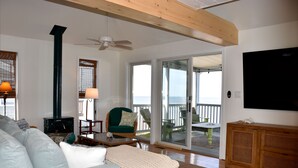 A living room with a sofa, a green armchair, a wooden cabinet, a television, and a fireplace. - Primehook Beach Bayfront Beauty (Milford)