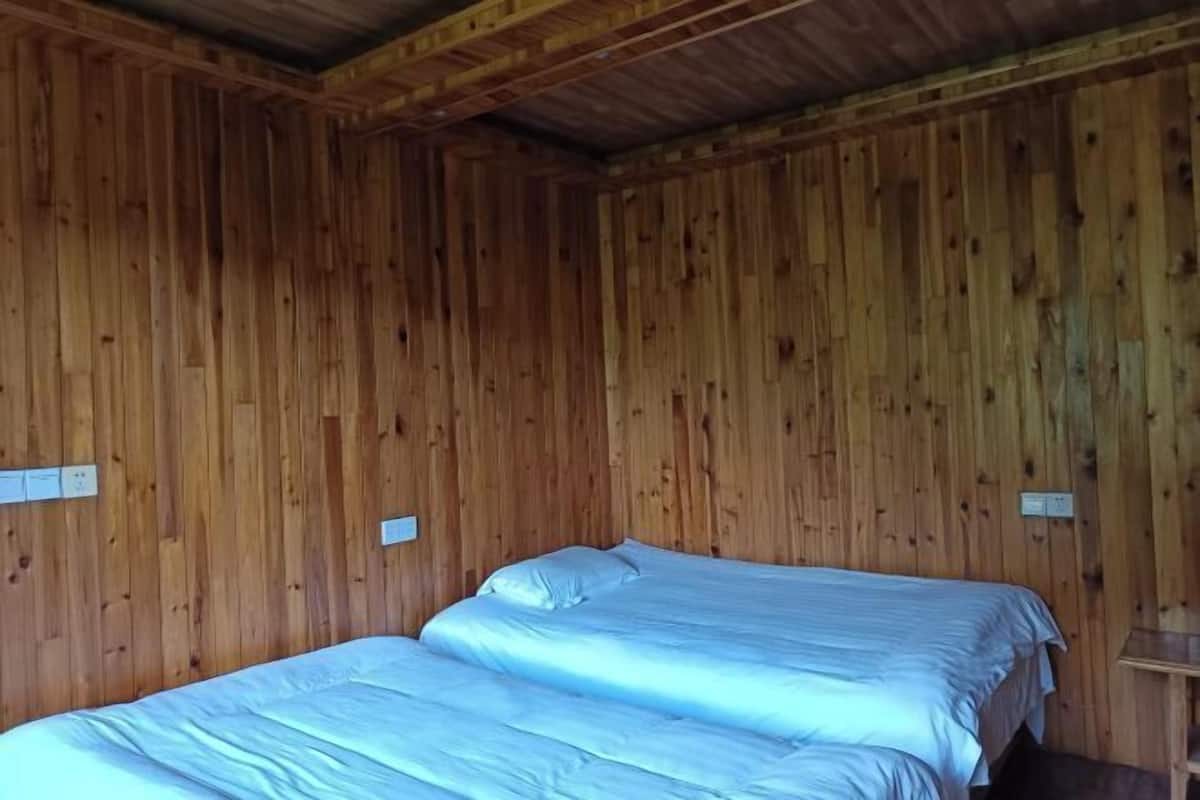 Habitación con paredes de madera y dos camas con ropa blanca.