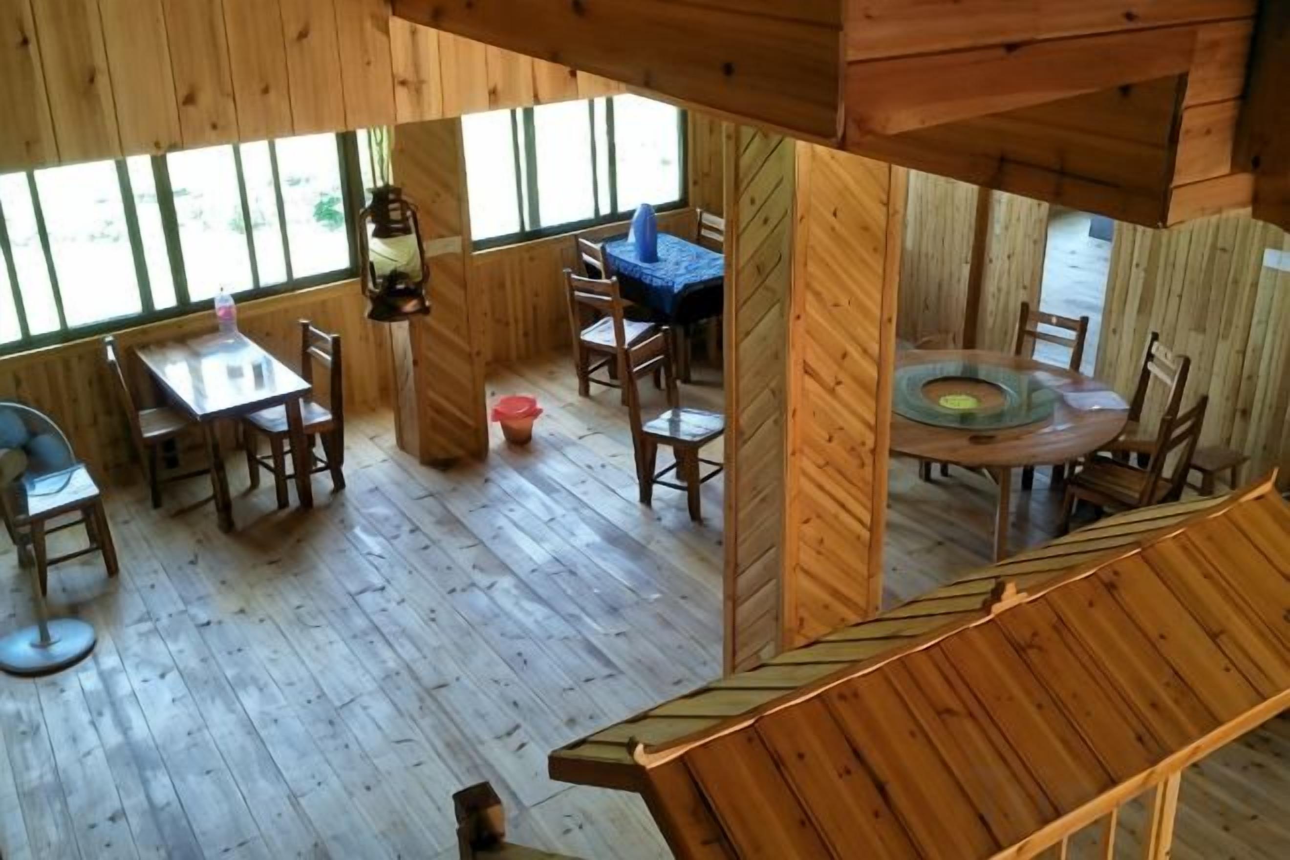 A wooden interior with a dining area, a circular table, and a blue chair.