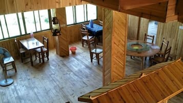 A wooden interior with a dining area, a circular table, and a blue chair.