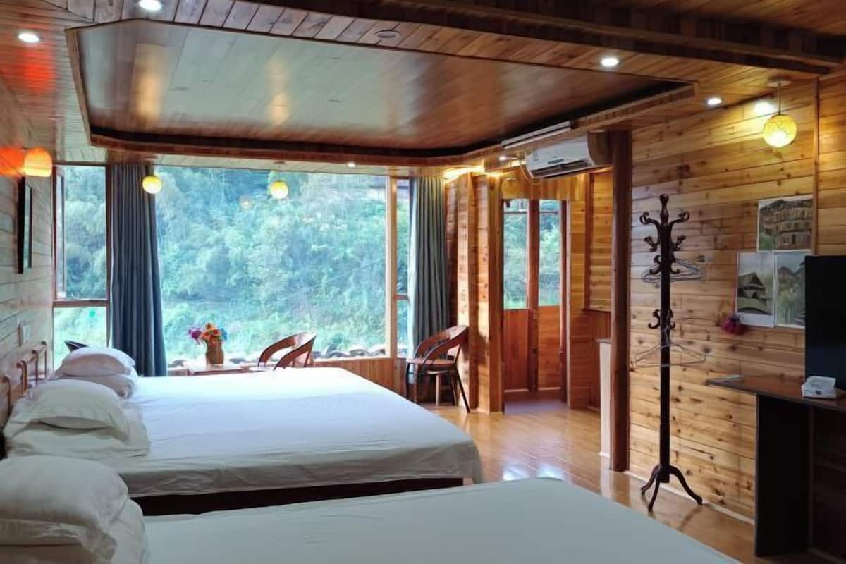 Una cabaña de madera con dos camas, una zona de comedor y vistas al bosque.