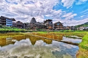 A traditional building with a reflection in a water body, surrounded by greenery. - Tongxiang Country House (Sanjiang)