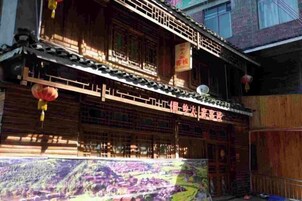 Un edificio de madera tradicional con varios balcones y un gran mural en la entrada.