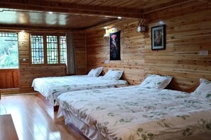 A wooden cabin-style room with two beds, a large window with a view of greenery, and a wall-mounted light fixture. - Tongxiang Country House (Sanjiang)