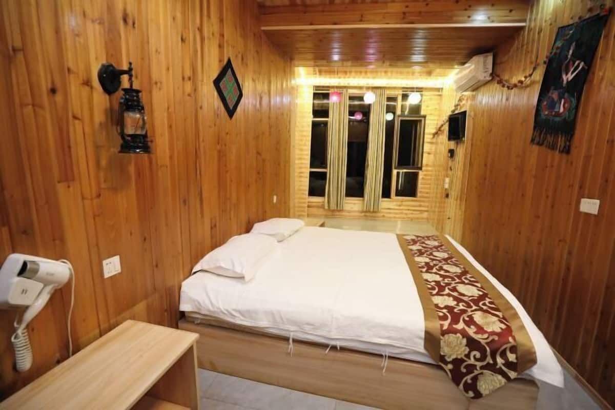 Una habitación con paneles de madera, una cama, una mesita de noche y un teléfono montado en la pared.