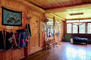 Ein Holzinnenraum mit einer großen Holztür, einem Wandventilator und einer Bank.