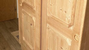 A wooden wardrobe with two doors and a handle, set in a room with wooden flooring. - FeWo 16 (Rottach.Apartments) Holiday apartment on Lake Tegernsee (Rottach-Egern)