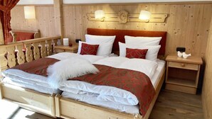 A wooden-framed bed with white and red bedding, two bedside tables with lamps, and a wooden headboard with wall-mounted lights. - FeWo 16 (Rottach.Apartments) Holiday apartment on Lake Tegernsee (Rottach-Egern)