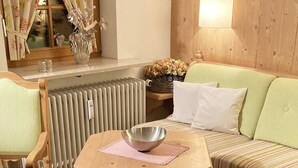 A cozy living room with a wooden table, striped armchairs, a sofa, and a radiator. - FeWo 17 (Rottach.Apartments) Holiday apartment on Lake Tegernsee (Rottach-Egern)