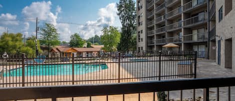 A swimming pool surrounded by a fence, with a multi-story building in the background.