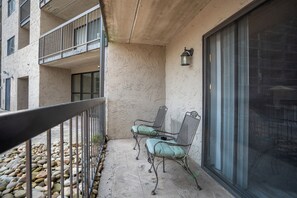 Ein Balkon mit Metallgeländer, zwei Stühlen, einem kleinen Tisch und einem Blumentopf.