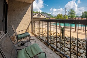 A balcony with two chairs, a pool, and a view of a house in the background. - Olde Gatlinburg 109 is a beautiful condo with private balcony located in downtow (Gatlinburg)