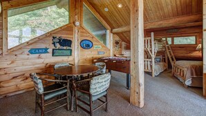 A cabin interior with a dining table, chairs, a wooden staircase, and a bed. - Ahh Time Flies at a mountain cabin with scenic view (Bryson City)