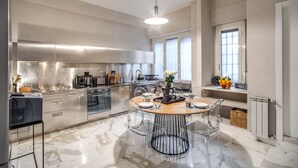 A modern kitchen with a central island, stainless steel appliances, and a dining area with clear chairs. - Spacious Luxury Family Home - 6 AC / WIFI / Heating / Elevator (Roma)
