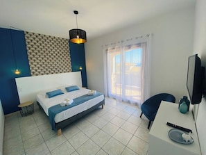 A modern bedroom with a large bed, a desk, a chair, and a TV. - Apartments in private residence with sea view, quiet and close to shops and beaches. (Solenzara)