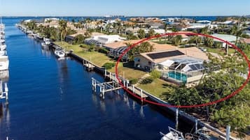 Un port de plaisance avec des bateaux amarrés, une maison avec une piscine et une zone encadrée en rouge qui met en évidence une section particulière.