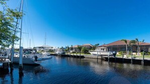 A marina with boats docked, a clear blue sky, and buildings with red roofs in the background. - Magical Family Oasis - Diamond Sunsets in Vacation Land -Sleeps10 -Pet Friendly  (Punta Gorda)