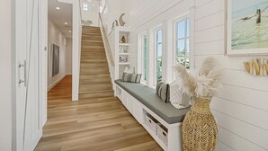 A staircase leading to a second floor, a bench with cushions, and a wall-mounted basket with feathers. - Lakeside Home@Cinnamon Shore South w/ Gourmet Kitchen+On-Site Amenities (Port Aransas)