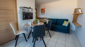 A compact living space with a dining area, a sofa, and a TV.