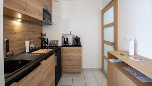 A compact kitchen with wooden cabinets, a black countertop, and a built-in microwave.