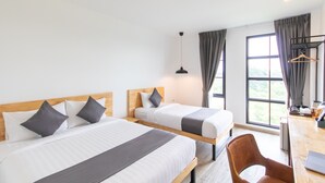 Quarto de hotel com duas camas, uma escrivaninha e uma cadeira.